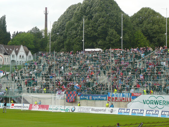 Die Stadt Wuppertal hat nicht genug Geld, um die Überdachung der Nordtribüne zu finanzieren, daher packen nun die Fans selbst mit an.<br />Bild: Rot-Blau.com”><figcaption>Die Stadt Wuppertal hat nicht genug Geld, um die Überdachung der Nordtribüne zu finanzieren, daher packen nun die Fans selbst mit an.<br />Bild: Rot-Blau.com</figcaption></figure>
<figure><img decoding=