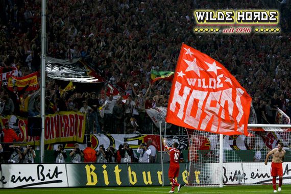 Podolski im Jahr 2009 nach Pokalerfolg vor der Kölner Südkurve.<br />Bild: WH96.de”><figcaption>Podolski im Jahr 2009 nach Pokalerfolg vor der Kölner Südkurve.<br />Bild: WH96.de</figcaption></figure>
<figure><img decoding=
