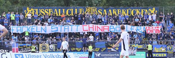 Spruchband der Saarbrücker-Fans.<br />Bild: Steven Mohr / Fußball-News Saarland”><figcaption>Spruchband der Saarbrücker-Fans.<br />Bild: Steven Mohr / Fußball-News Saarland</figcaption></figure>
<figure><img decoding=