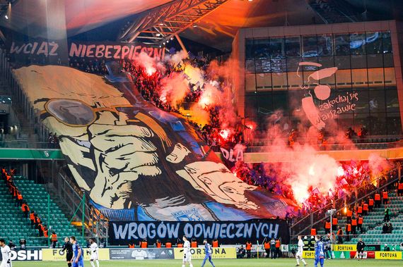 Blockfahne und Bengalische Fackeln der Lech-Fans.<br />Bild: legionisci.com“><figcaption>Blockfahne und Bengalische Fackeln der Lech-Fans.<br />Bild: legionisci.com</figcaption></figure>
<figure><img decoding=