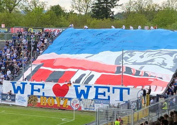 Die Blockfahne der Ultras von Hansa Rostock.<br />Bild: 88hop2ping55″><figcaption>Die Blockfahne der Ultras von Hansa Rostock.<br />Bild: 88hop2ping55</figcaption></figure>
<figure><img decoding=