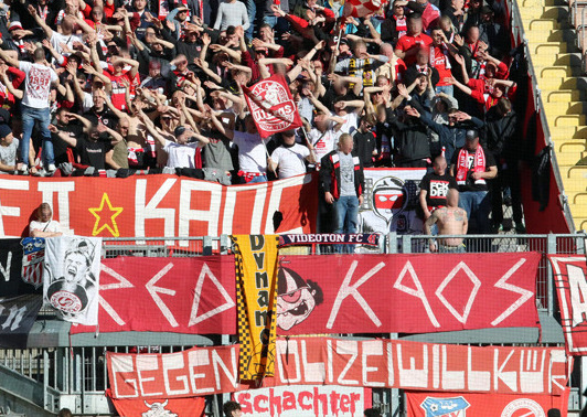 Diese Zaunfahne nimmt das Red Kaos mit zu Auswärtsspielen.<br />Bild: www.der-betze-brennt.de”><figcaption>Diese Zaunfahne nimmt das Red Kaos mit zu Auswärtsspielen.<br />Bild: www.der-betze-brennt.de</figcaption></figure>
<figure><img decoding=