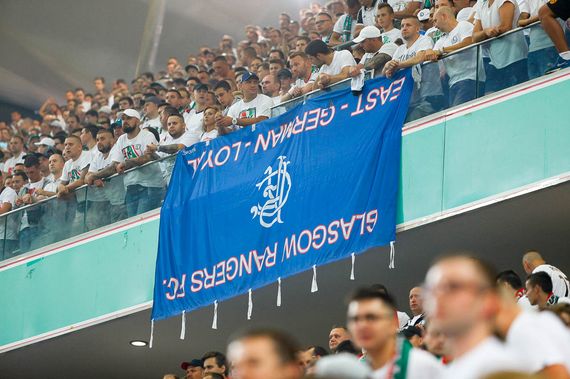 Die geklaute Rangers FC-Fahne aus Ostdeutschland in den Händen von Legia-Fans.<br />    <button type=